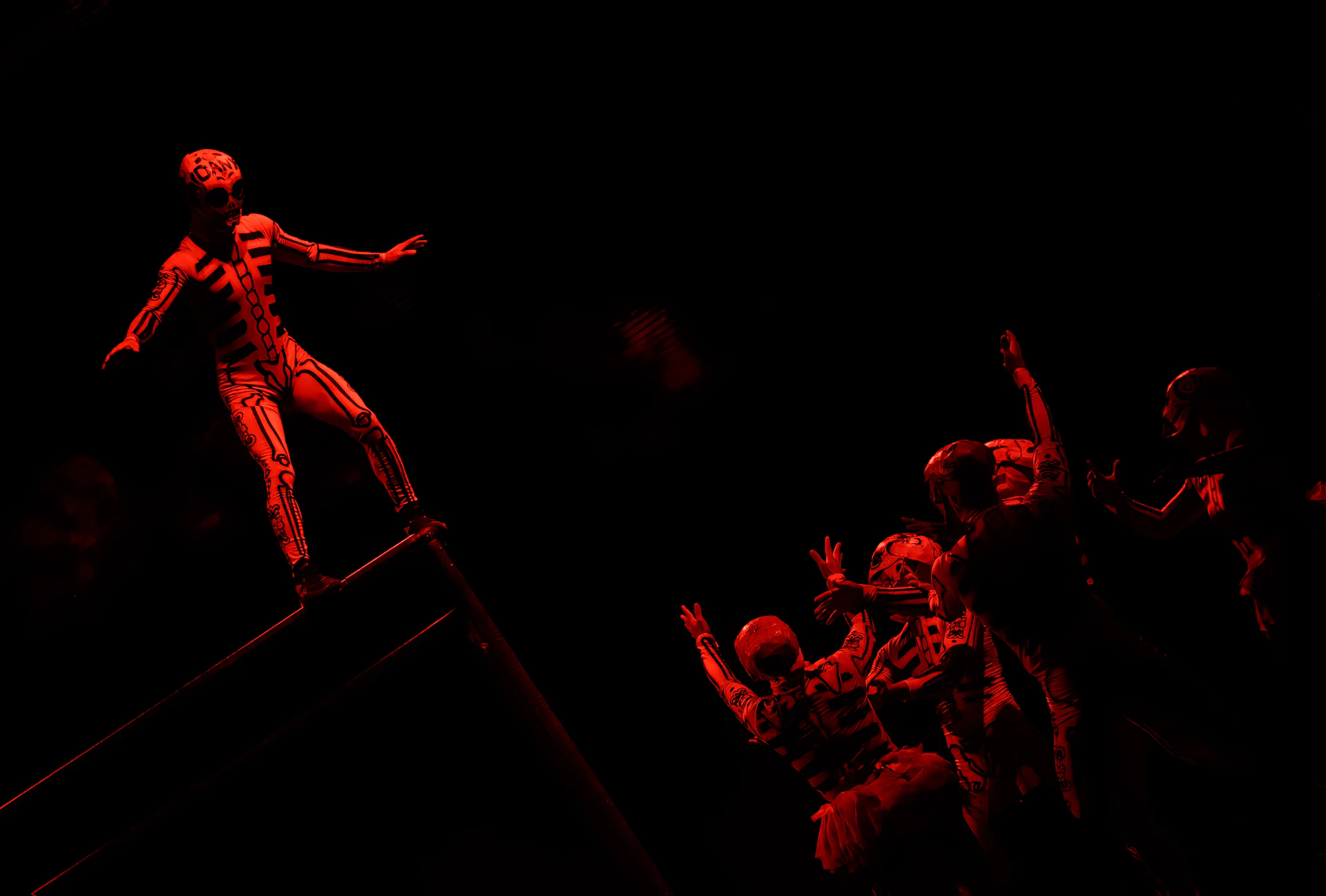 Circus performers in red stage costumes on a dark stage