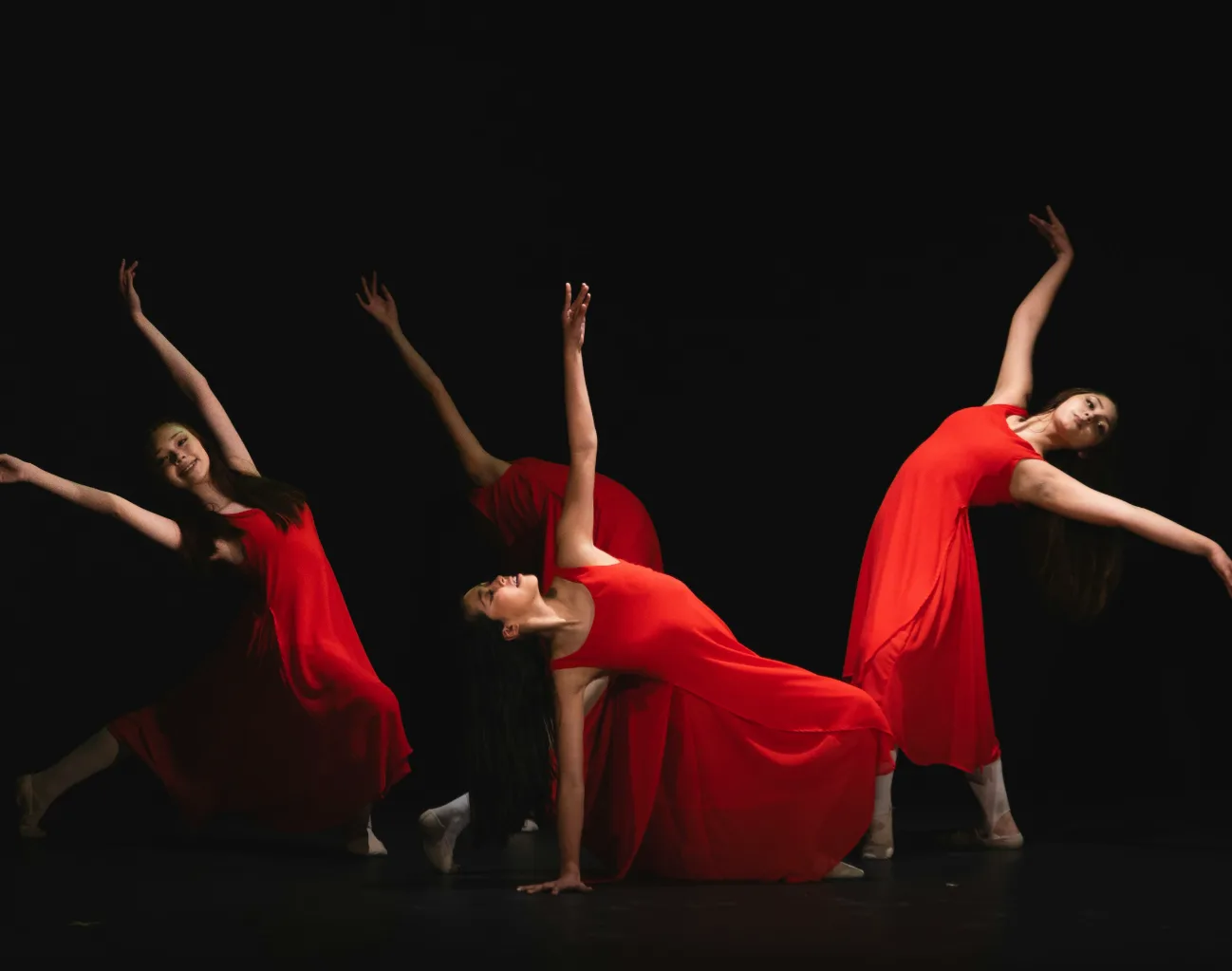 Professional dancers in red stage costumes performing to music