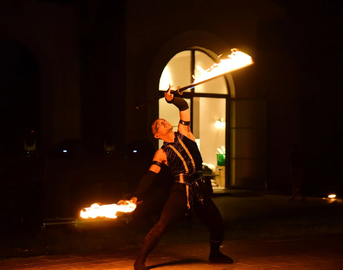 Fire performer spinning flaming fans outside a venue