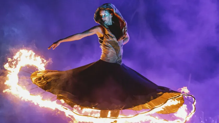 Female fire dancer swirling a flaming skirt during a night performance