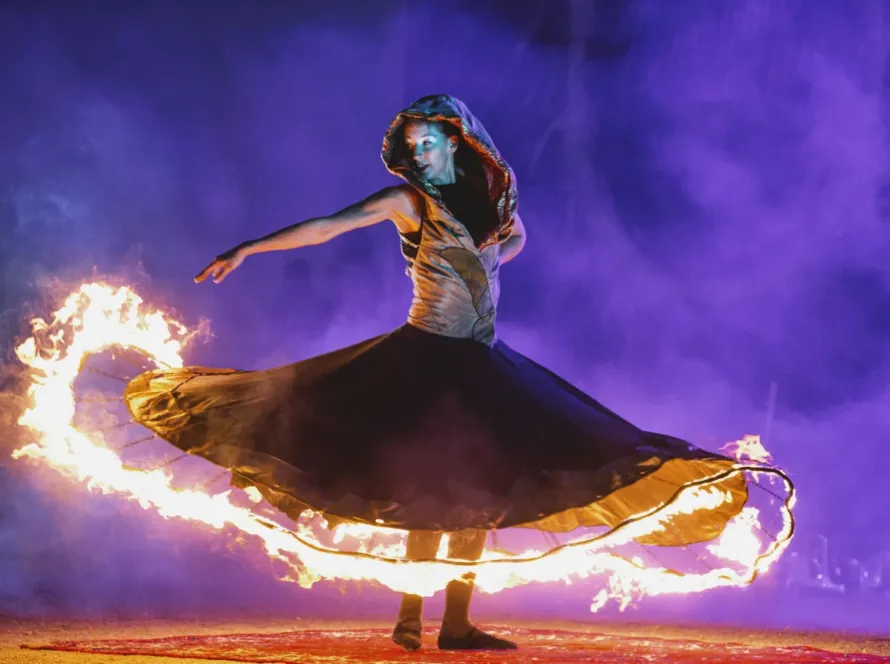 Female fire dancer swirling a flaming skirt during a night performance