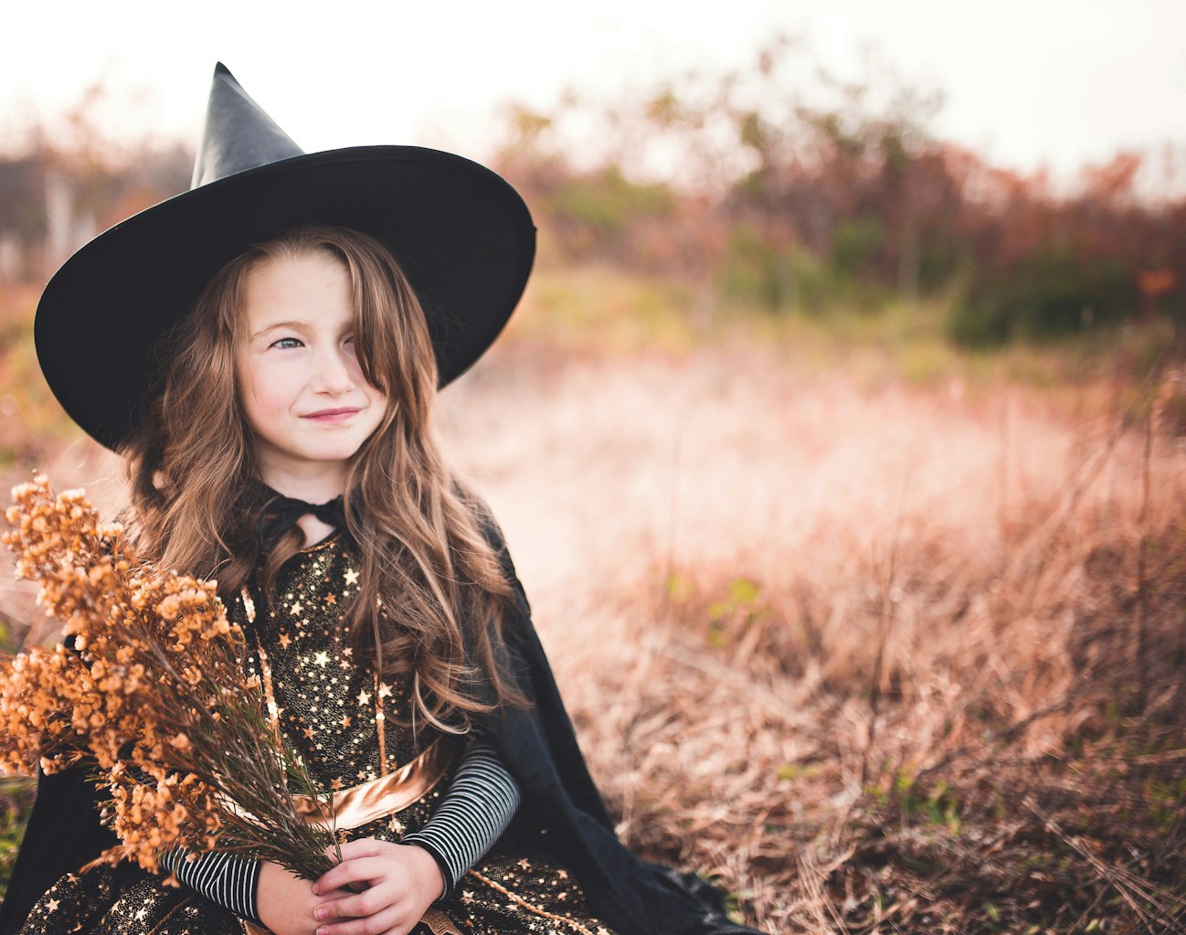 Young girl wearing a black witch costume and hat for Halloween