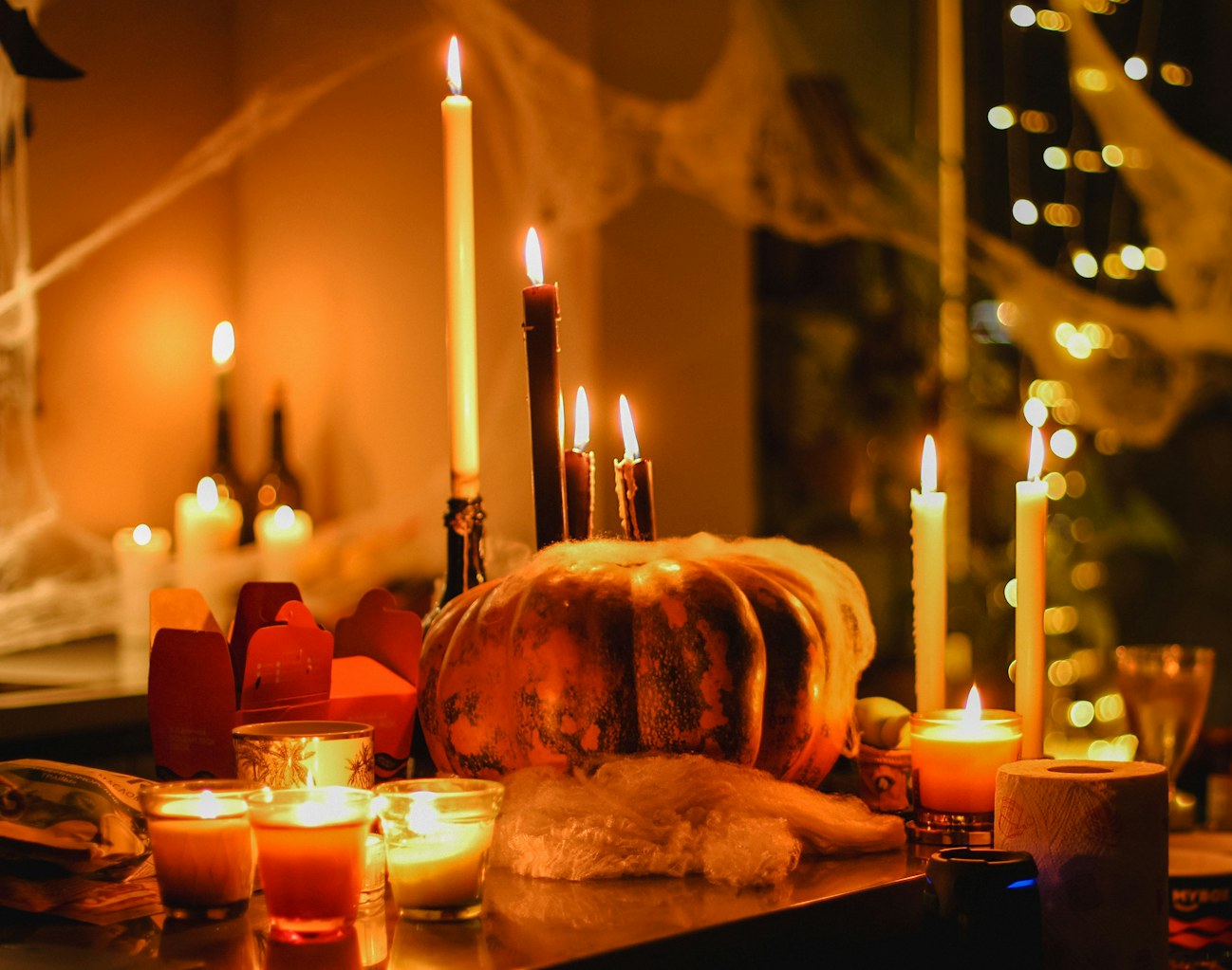 Halloween party decorations with glowing candles, pumpkins and spider webs creating a spooky atmosphere